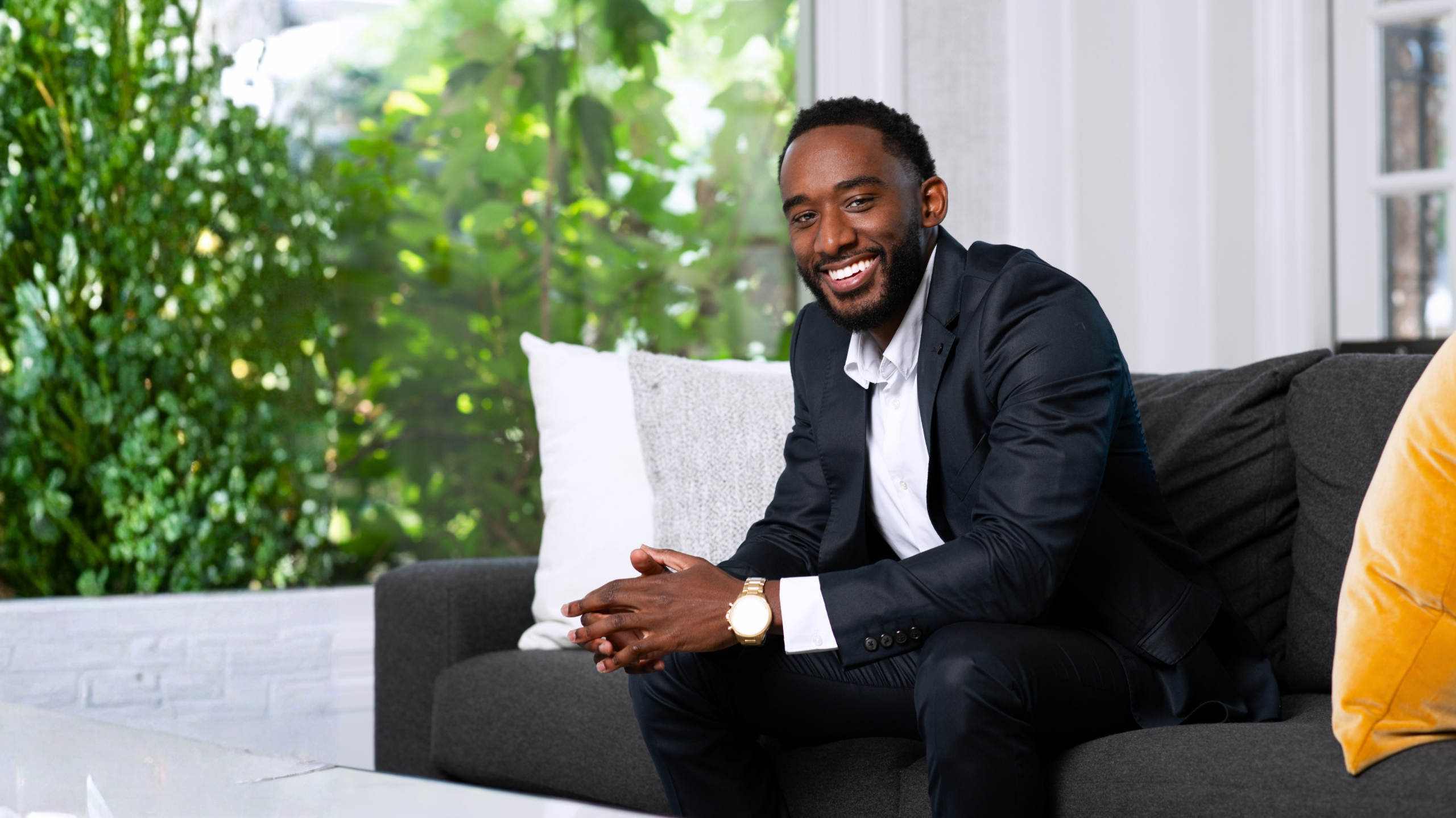Christian Neil Jones seated on a sofa, smiling